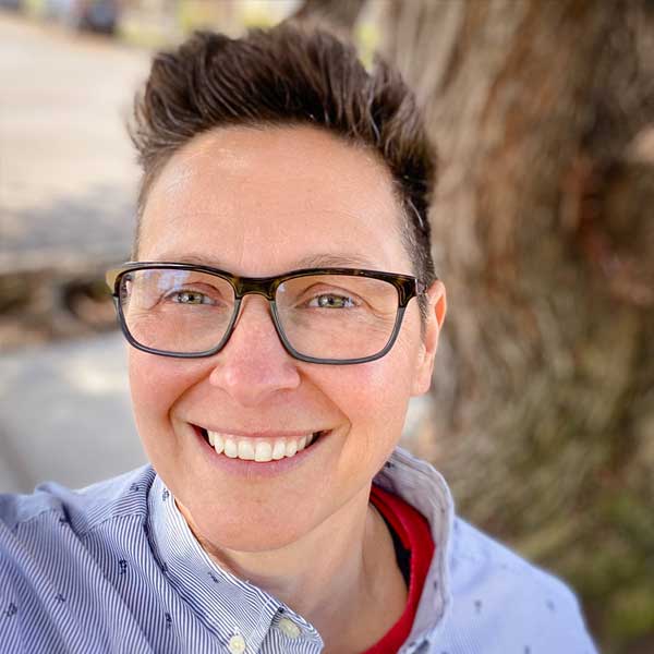 Headshot of Mandy Love, graphic designer standing in front of a tree